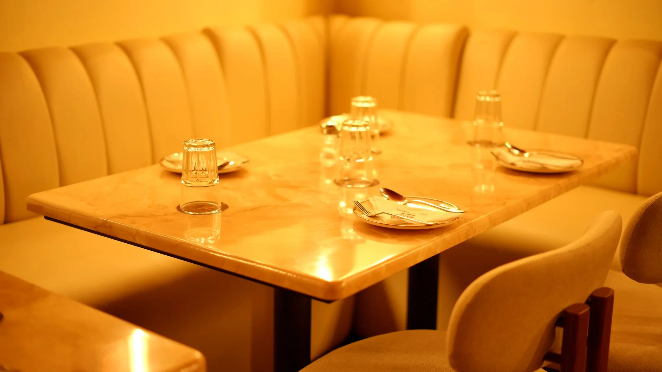 Restaurant seating area in Mysore with a marble dining table, clean plates, and comfortable cushioned seating.