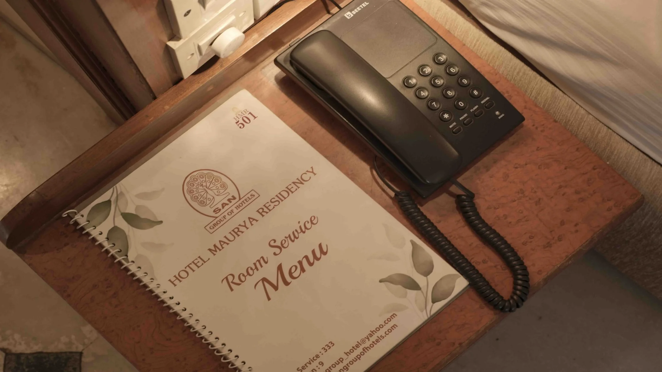 Hotel room service menu and telephone at Hotel Maurya Residency, useful for planning your Mysore vacation essentials.