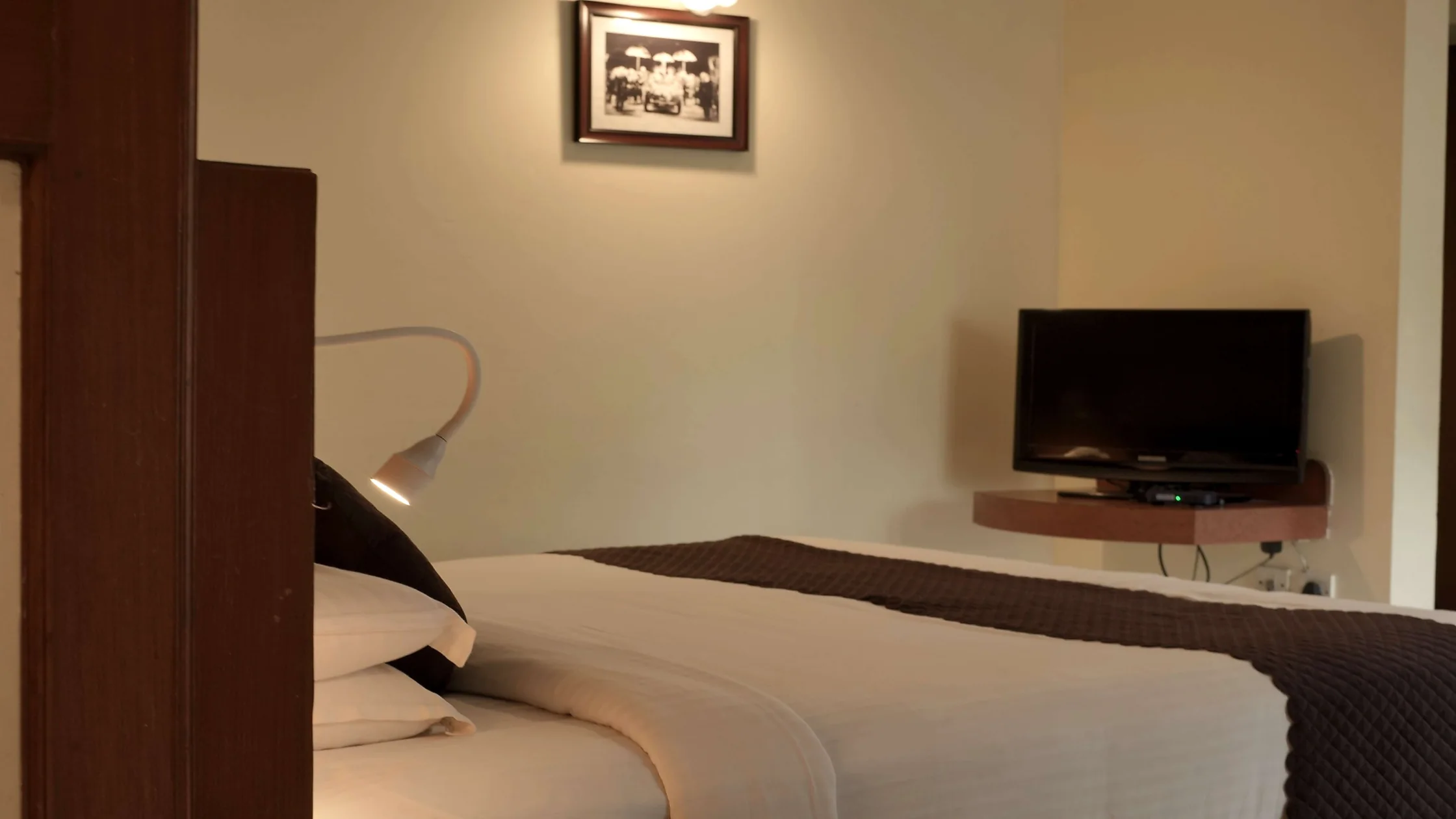 Family-friendly hotel room in Mysore with a comfortable bed, television, and bedside reading light.