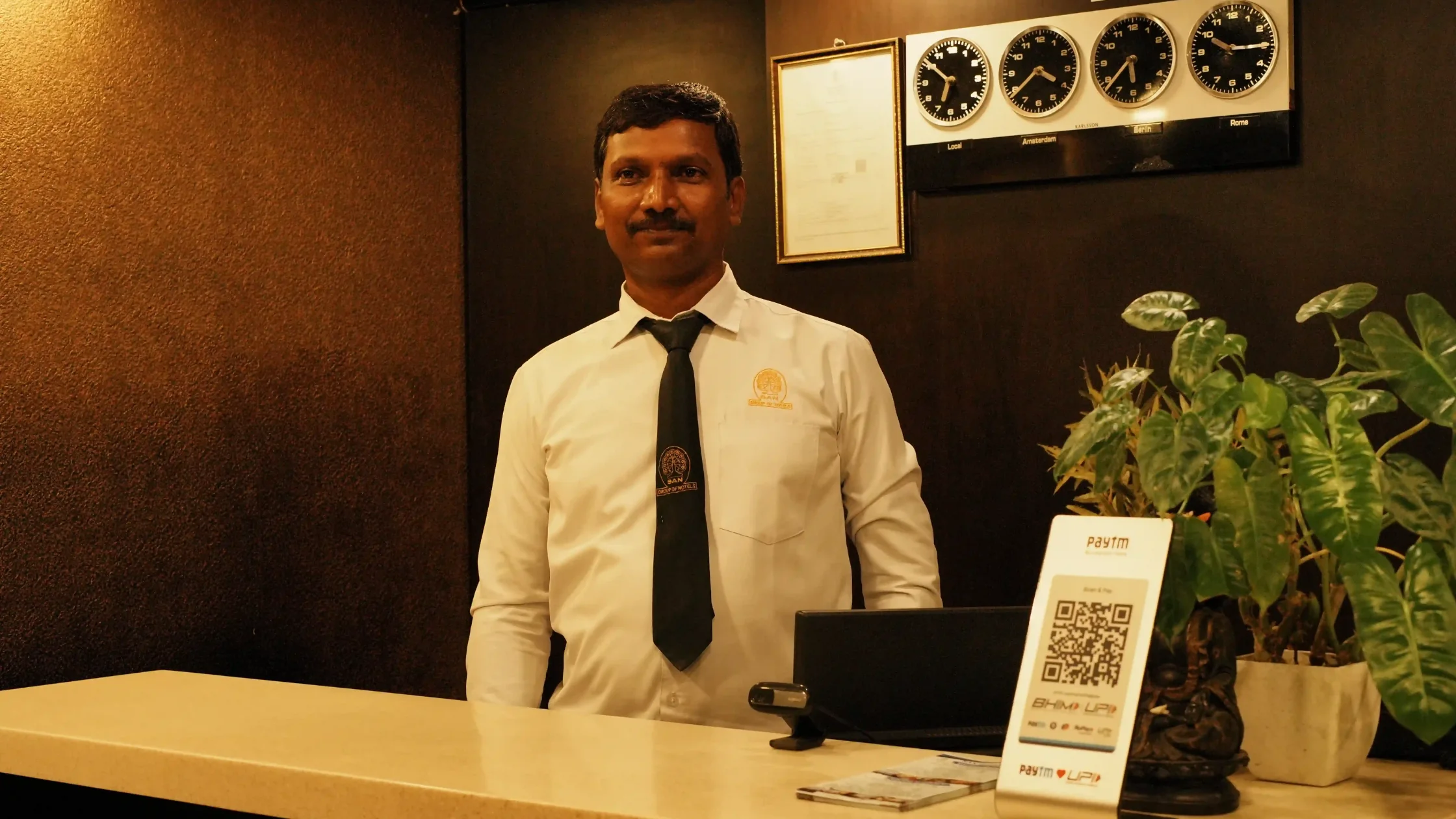 Hotel receptionist at the front desk of a Mysore hotel, offering a welcoming check-in experience for first-time visitors.