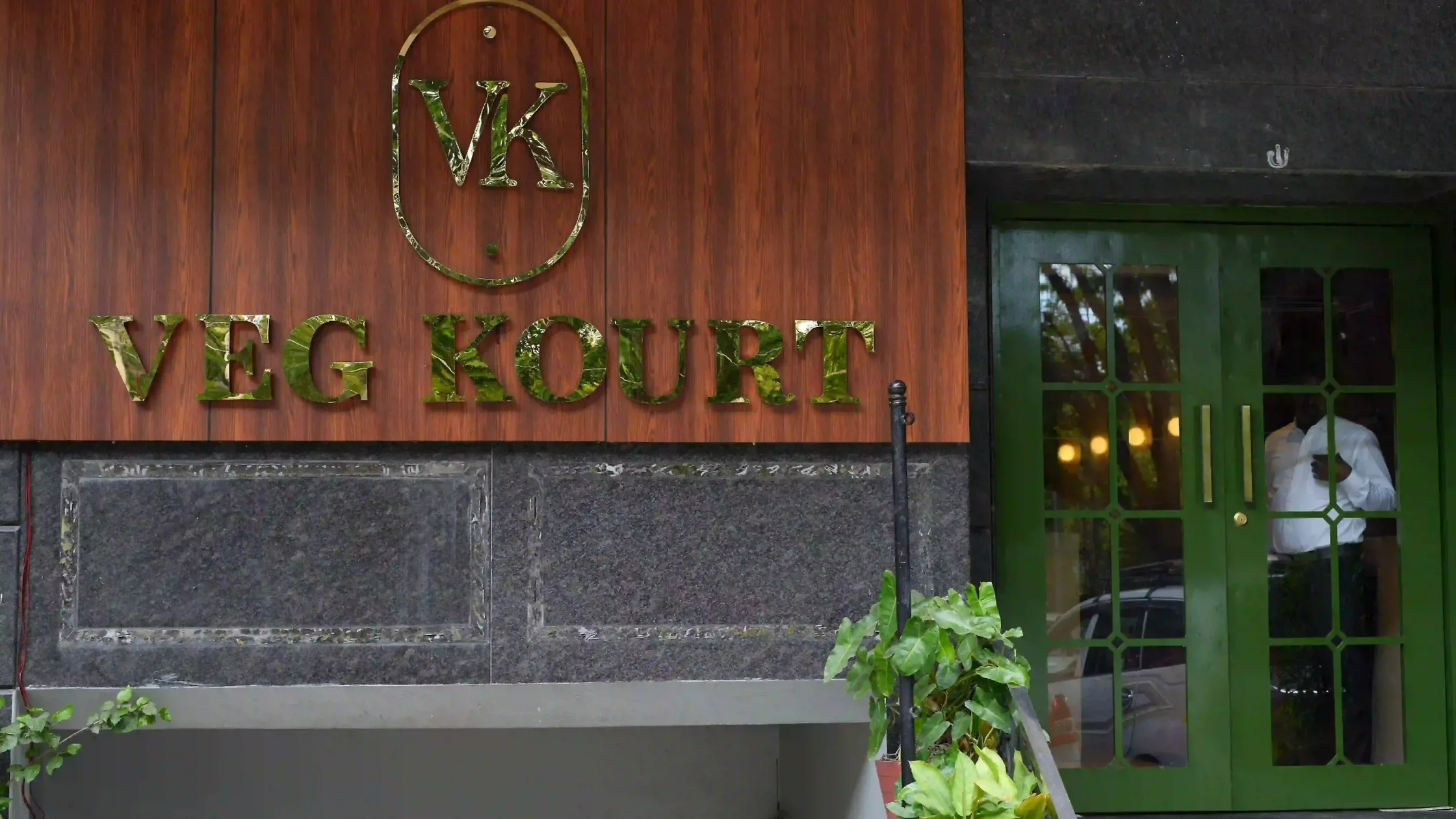 Veg Kourt restaurant entrance in Mysore with green doors and wooden signage.